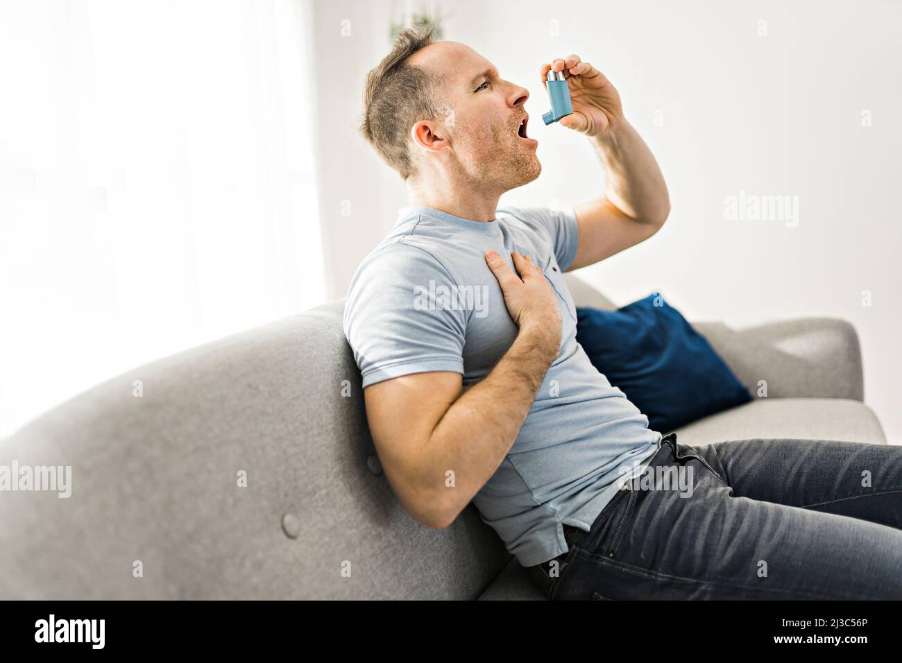 Man using asthma inhaler near cat at home. Health care Stock Photo Alamy