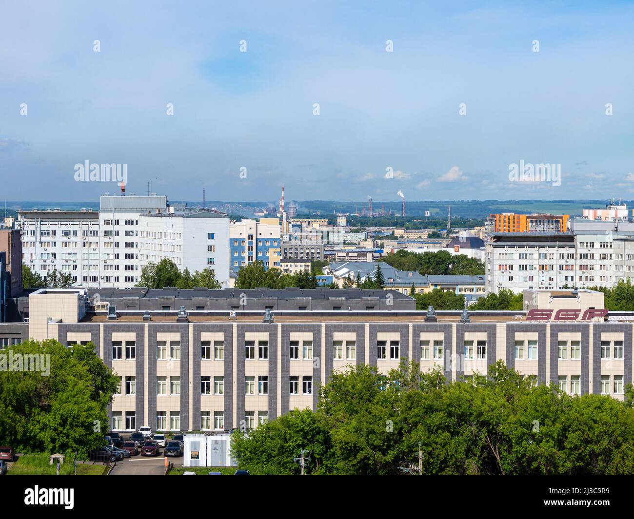 Kemerovo, Russia - 24 june 2021. Urban landscape from a height - an industrial area with smoking chimneys and a forest with agricultural land on the h Stock Photo