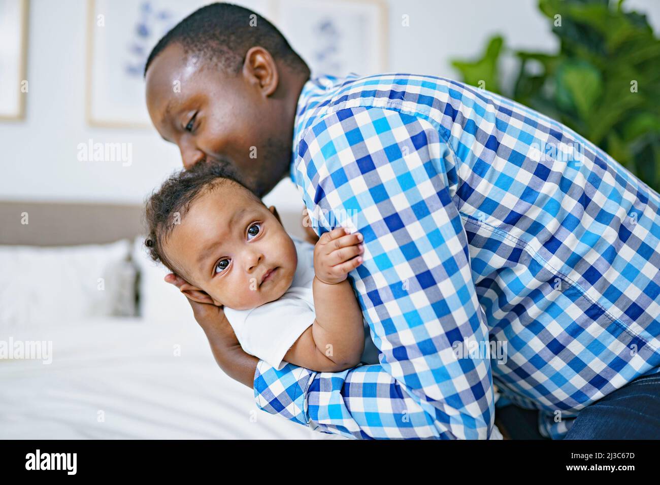 happy young African man playing with his little baby while lying in bed Stock Photo