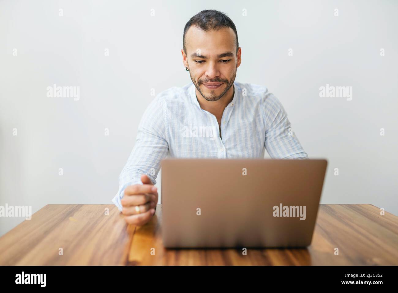 Portrait young mexican attractive businessman working at modern home office with computer laptop Stock Photo
