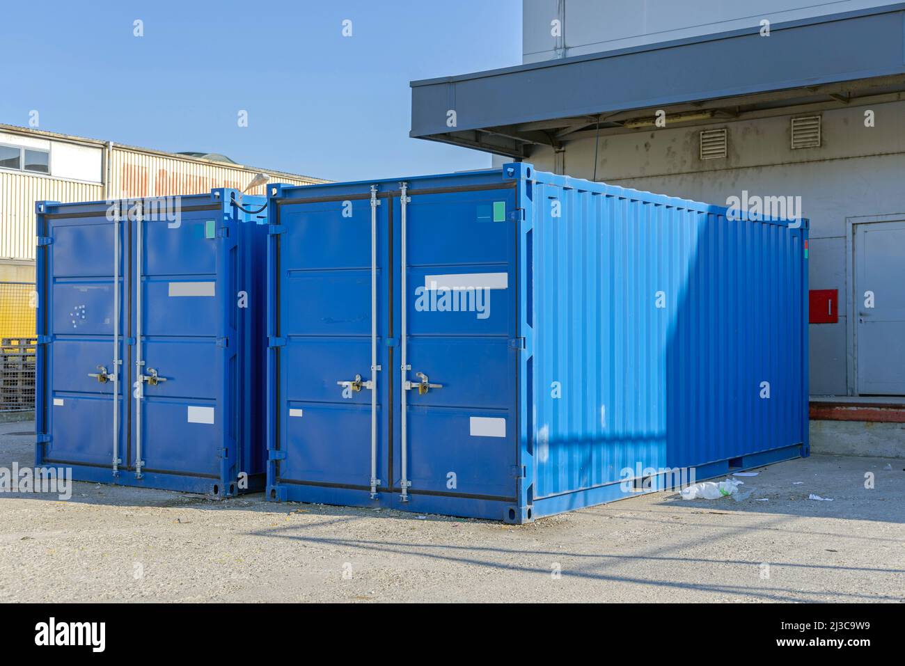 Two Blue Shipping Cargo Containers in Front of Warehouse Temporary