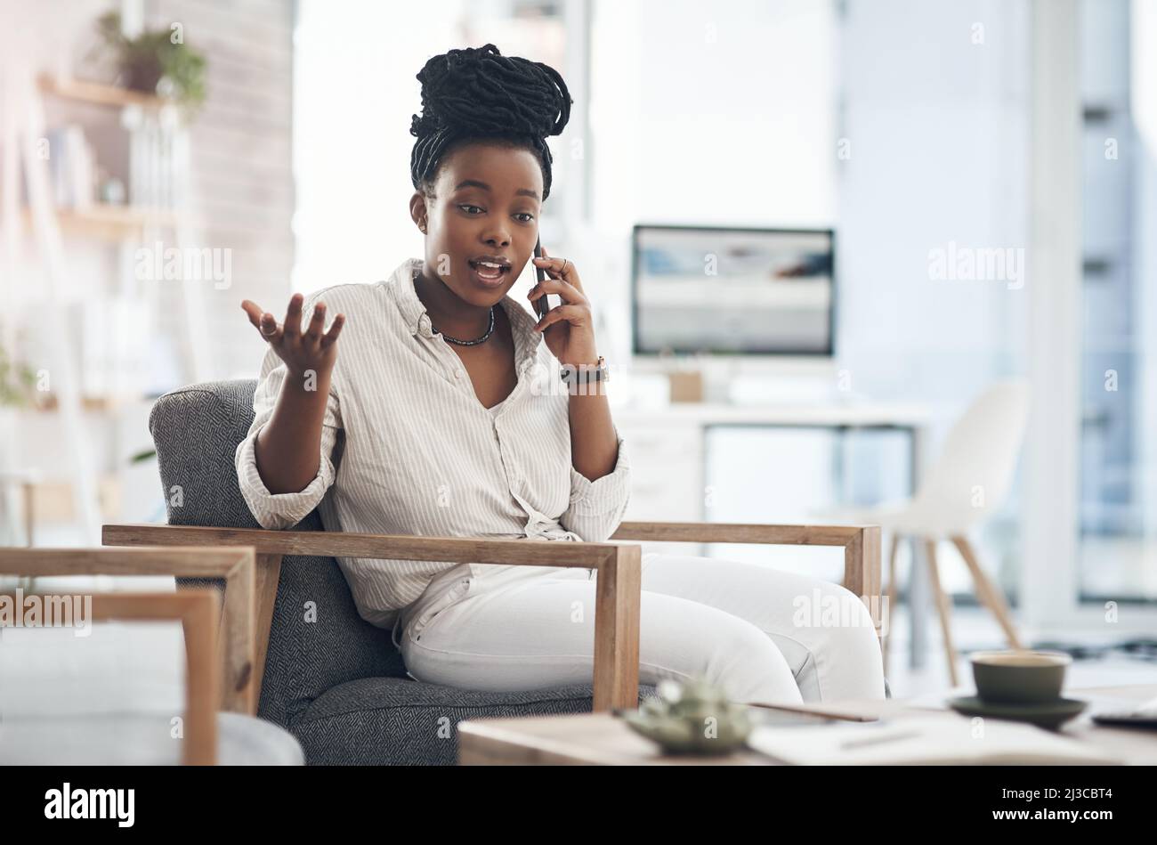 Tell me all the hot gossip. Shot of a young businesswoman using her smartphone to make phone calls at the office. Stock Photo
