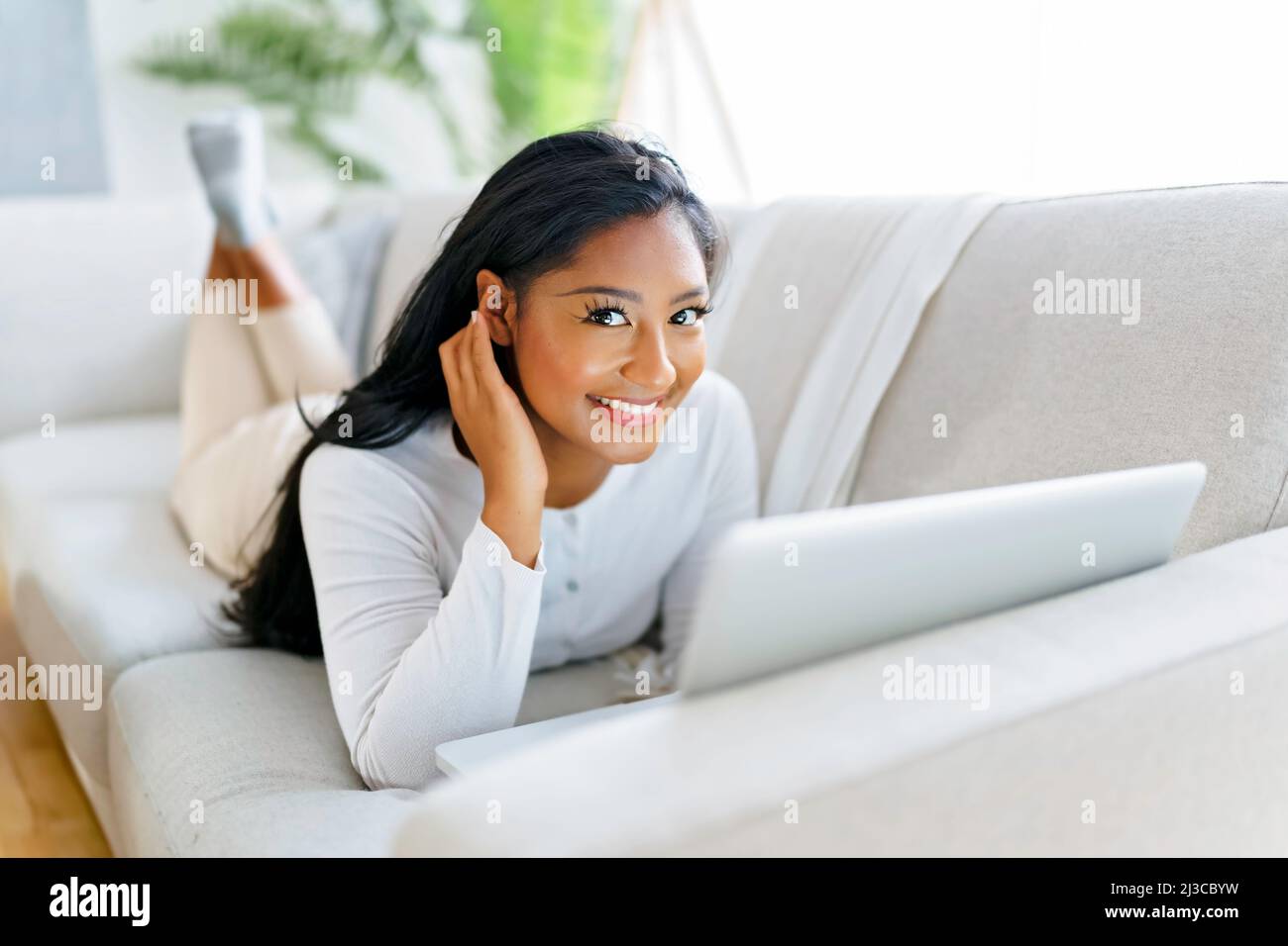 black woman using her laptop on cosy sofa at home Stock Photo - Alamy