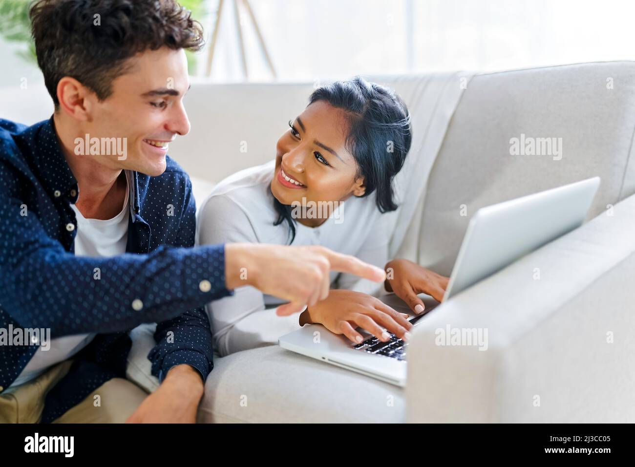 Young couple relaxing on sofa with laptop Stock Photo - Alamy