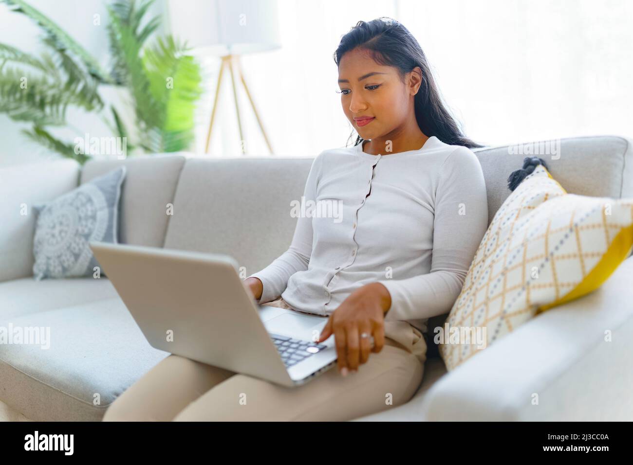 black woman using her laptop on cosy sofa at home Stock Photo - Alamy