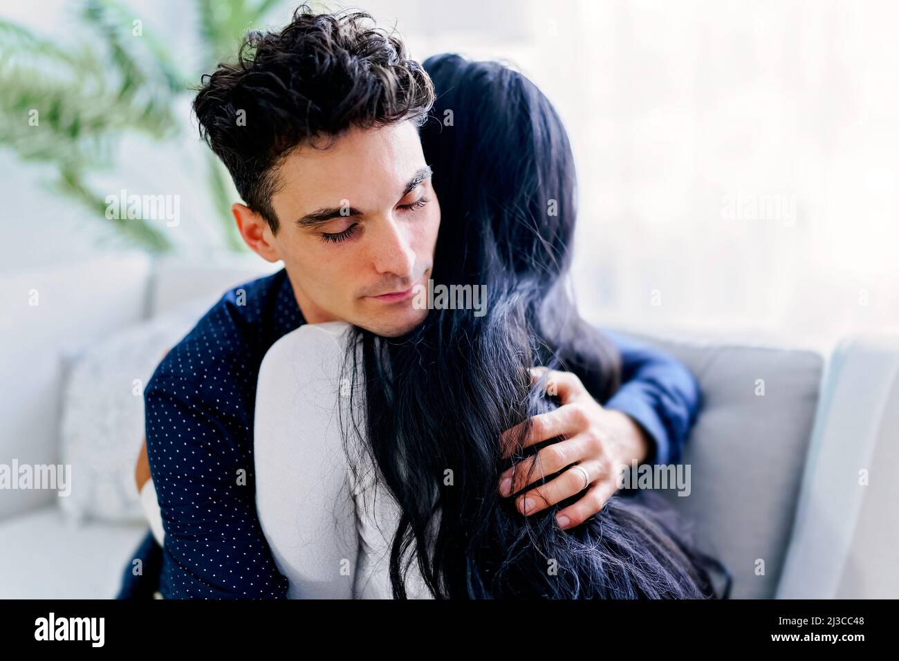 Attractive couple cuddling on the couch at home in the living room