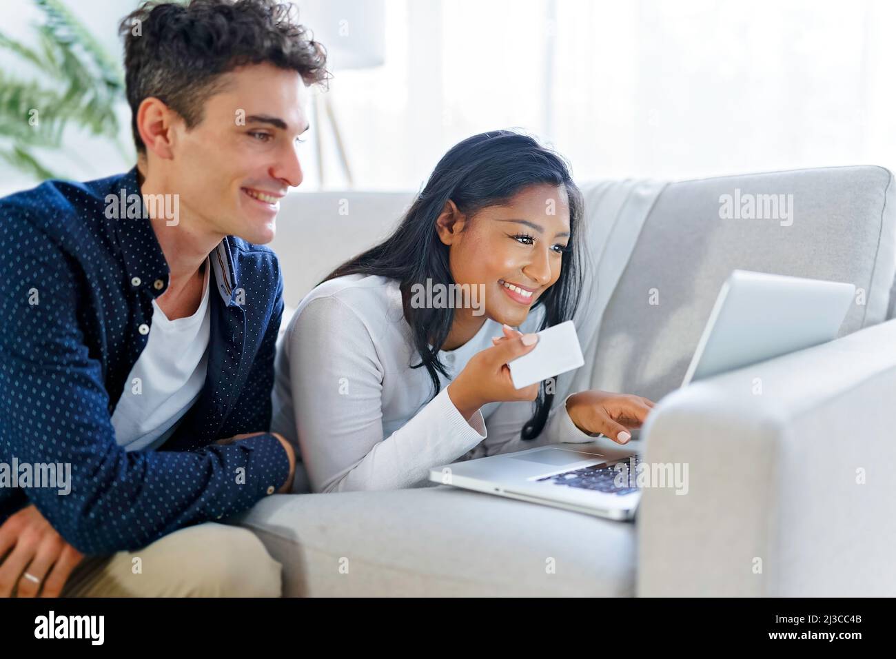 Young couple relaxing on sofa with laptop Stock Photo - Alamy