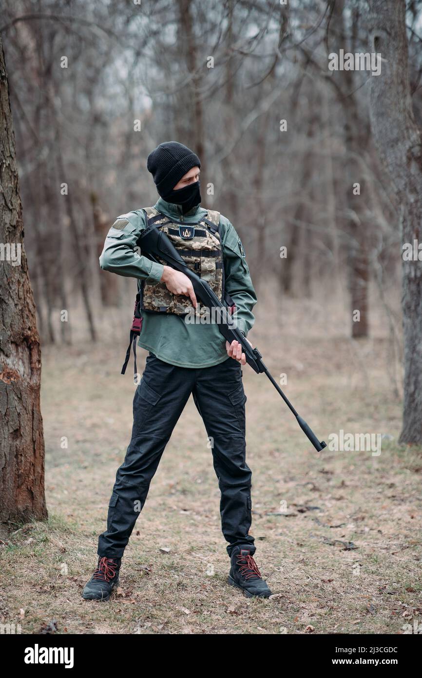 Young man stands with pump gun in his hands weared in body armor and ...