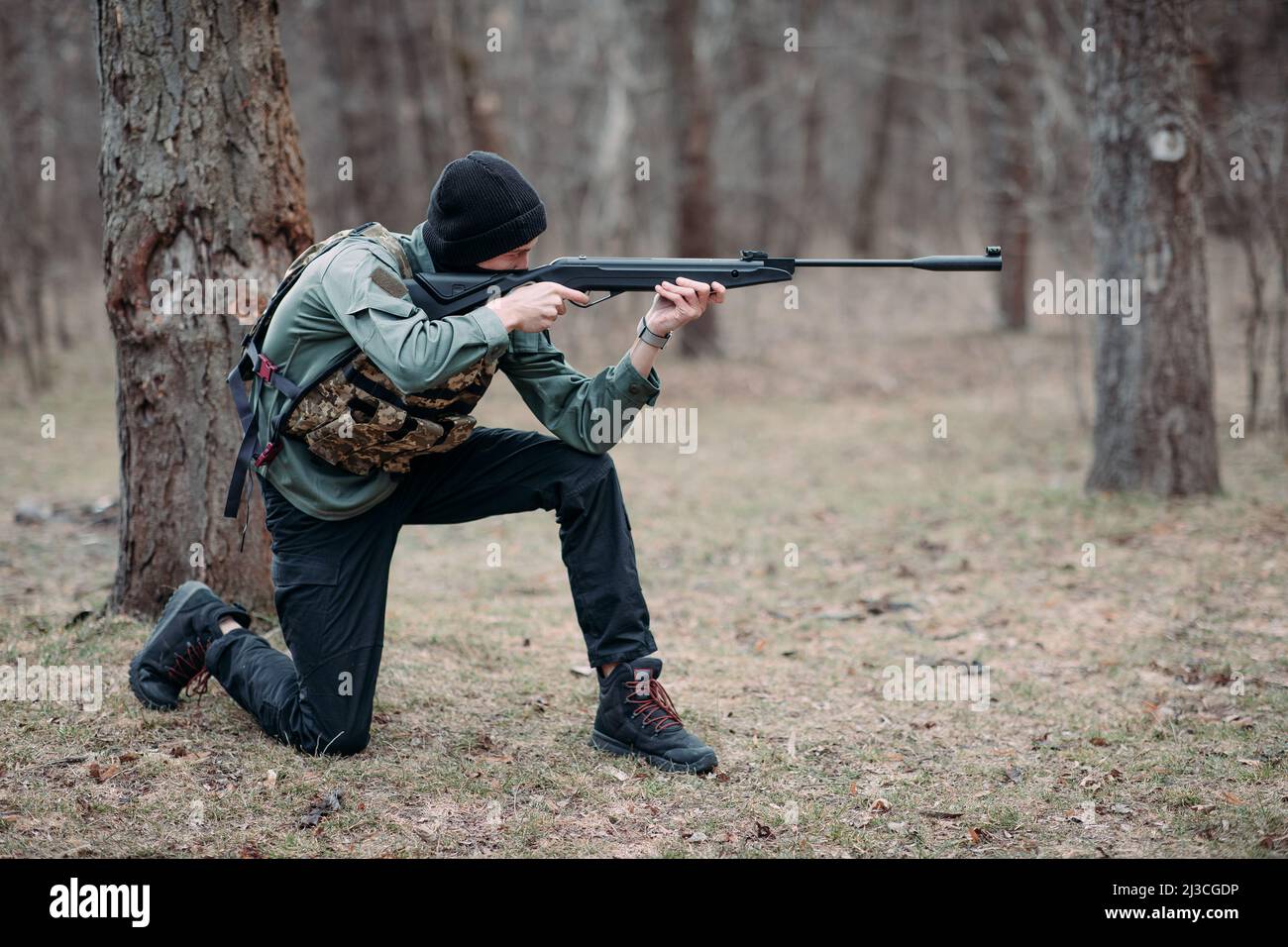 Young man practices and aims from pump gun weared in body armor and ...