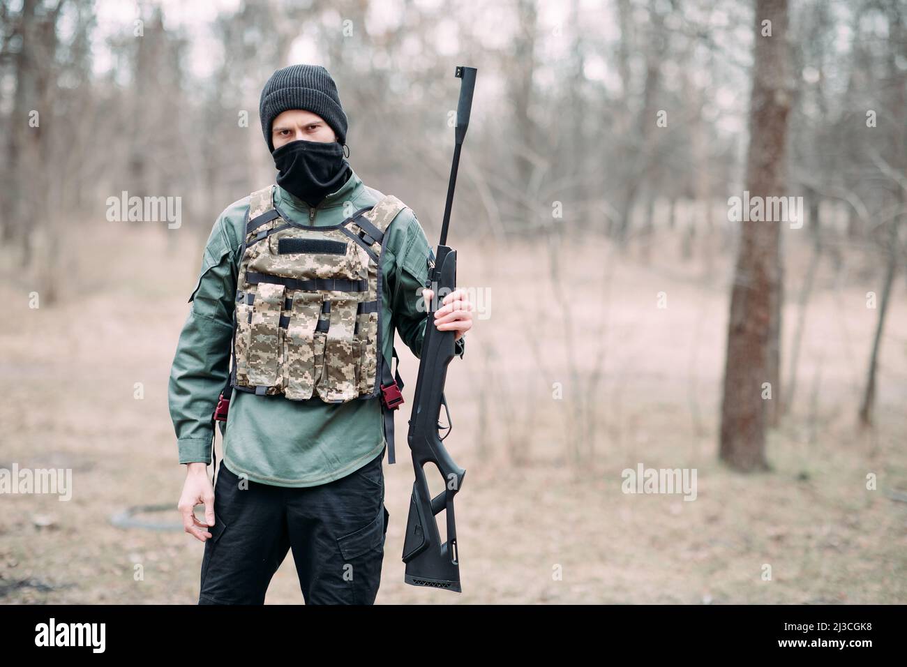 Young man stands with pump gun in his hand weared in body armor and ...