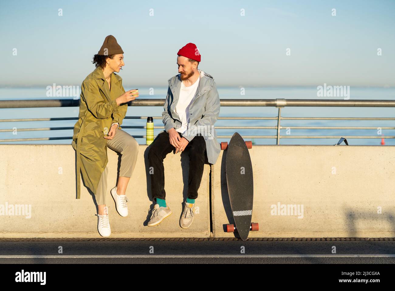 Young couple of hipster skateboarders relax after skateboarding training sitting on concrete bridge Stock Photo