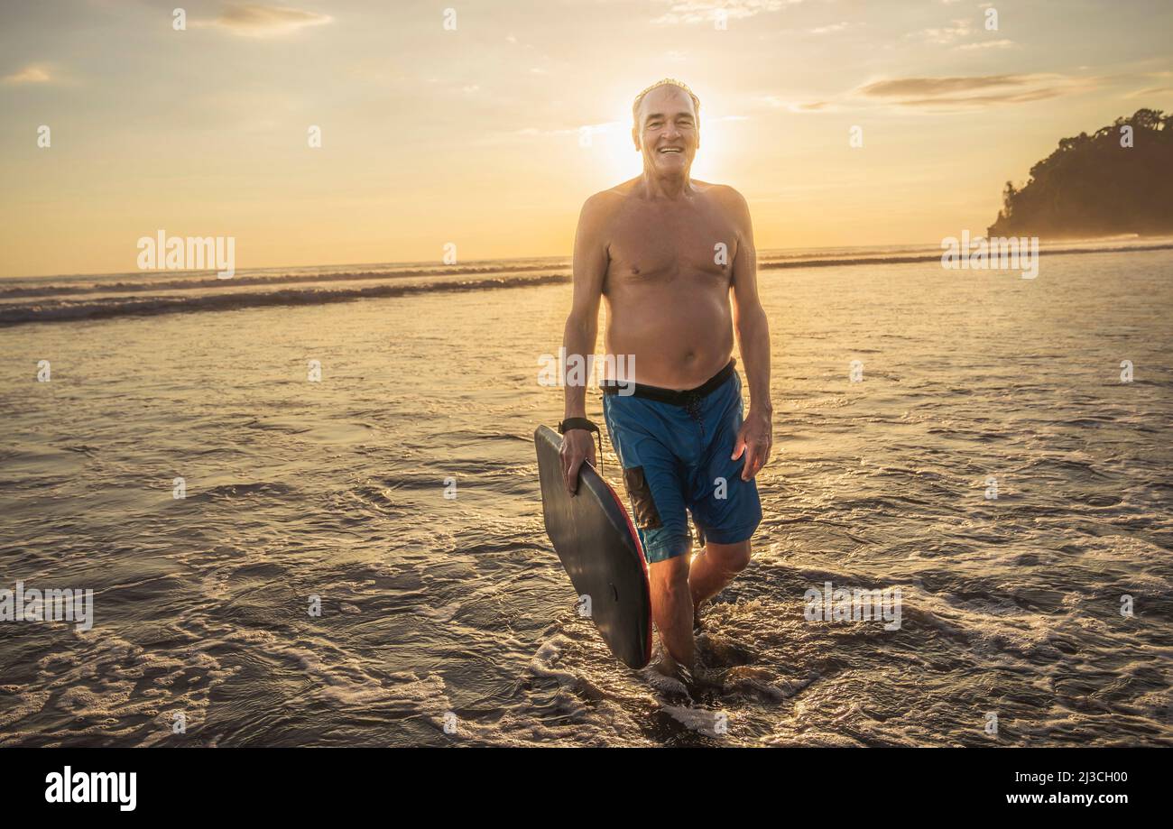 man with Boogie board on the beach at the sunset Stock Photo