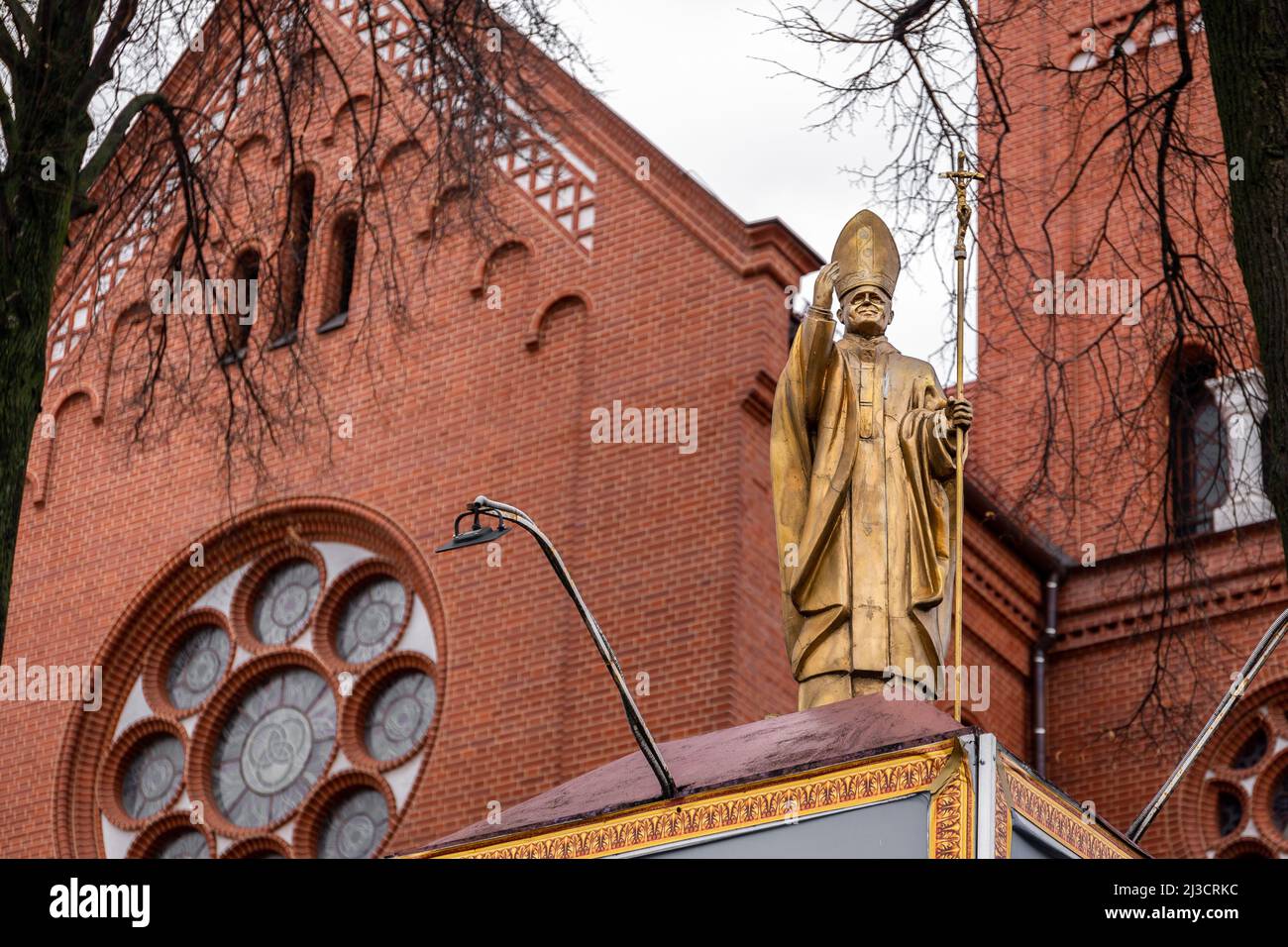 Minsk, Belarus, 04.11.21. Saint John Paul II Pope golden statue in front of Church of Saints Simon and Helena (Red Church) polish catholic church in M Stock Photo