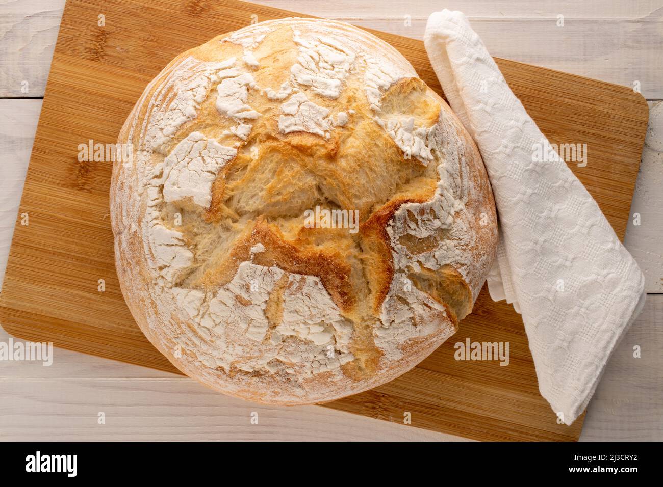 One loaf of fresh fragrant white wheat bread on a bamboo board, close-up, top view. Stock Photo