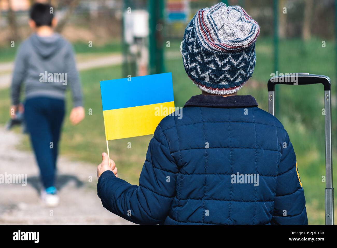 Children or kids with winter clothes, hat and Ukrainian flag, profile of the child is on the flag. War in Ukraine, caused by Putin and Russia, refugee Stock Photo