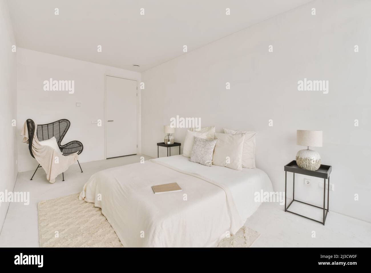 Comfortable bed with decorative cushions placed between bedside tables