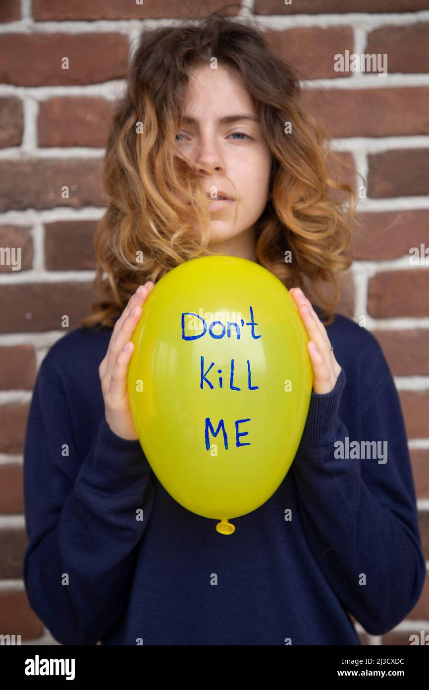 desperate teenage girl with a yellow balloon with the inscription don't kill me. Ukrainians are against the war. Feelings of fear, despair, drawing at Stock Photo
