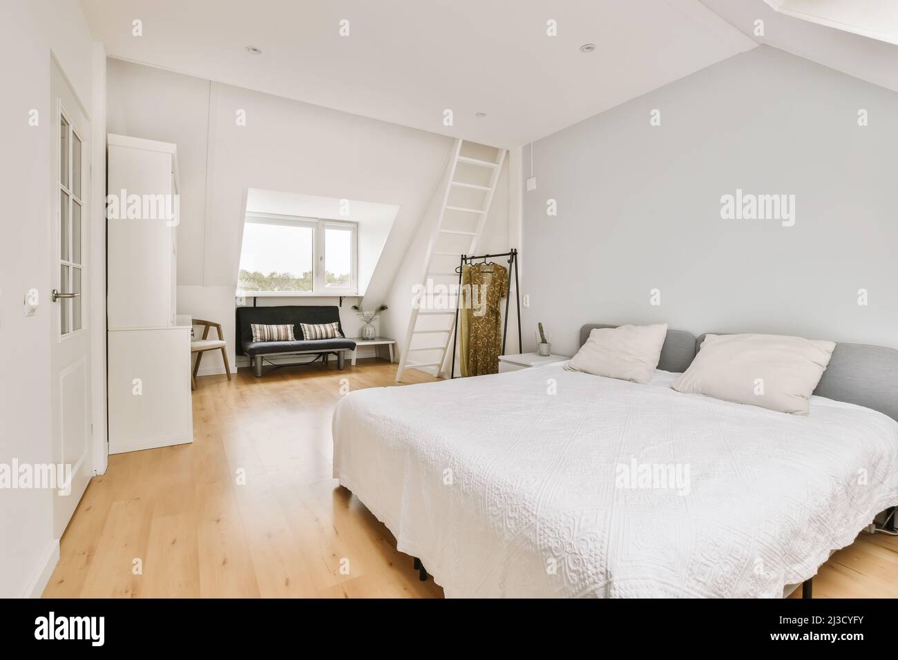 Interior of modern bedroom with comfortable bed and sofa placed on