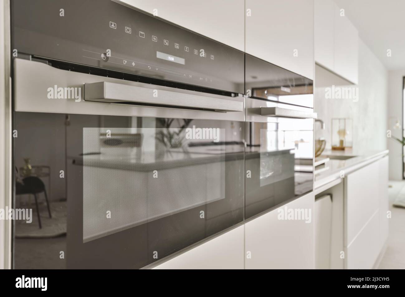 Contemporary ovens with shiny surface built in cupboards in kitchen in