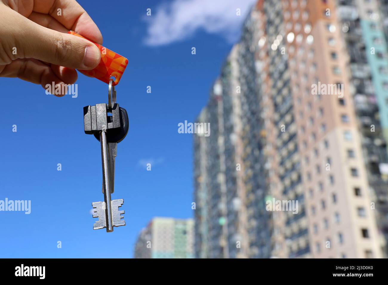 House keys in male hand on background of new buildings. Real estate agent, moving home or renting property Stock Photo