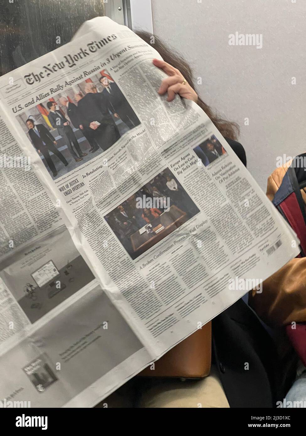 Woman reads the New York Times on a subway train in New York City. Stock Photo