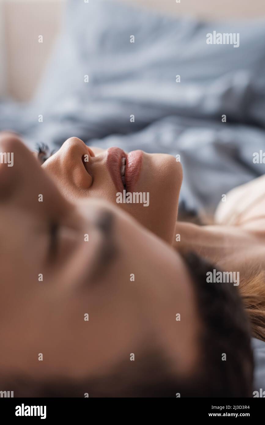 Young woman lying near blurred boyfriend on bed at home Stock Photo