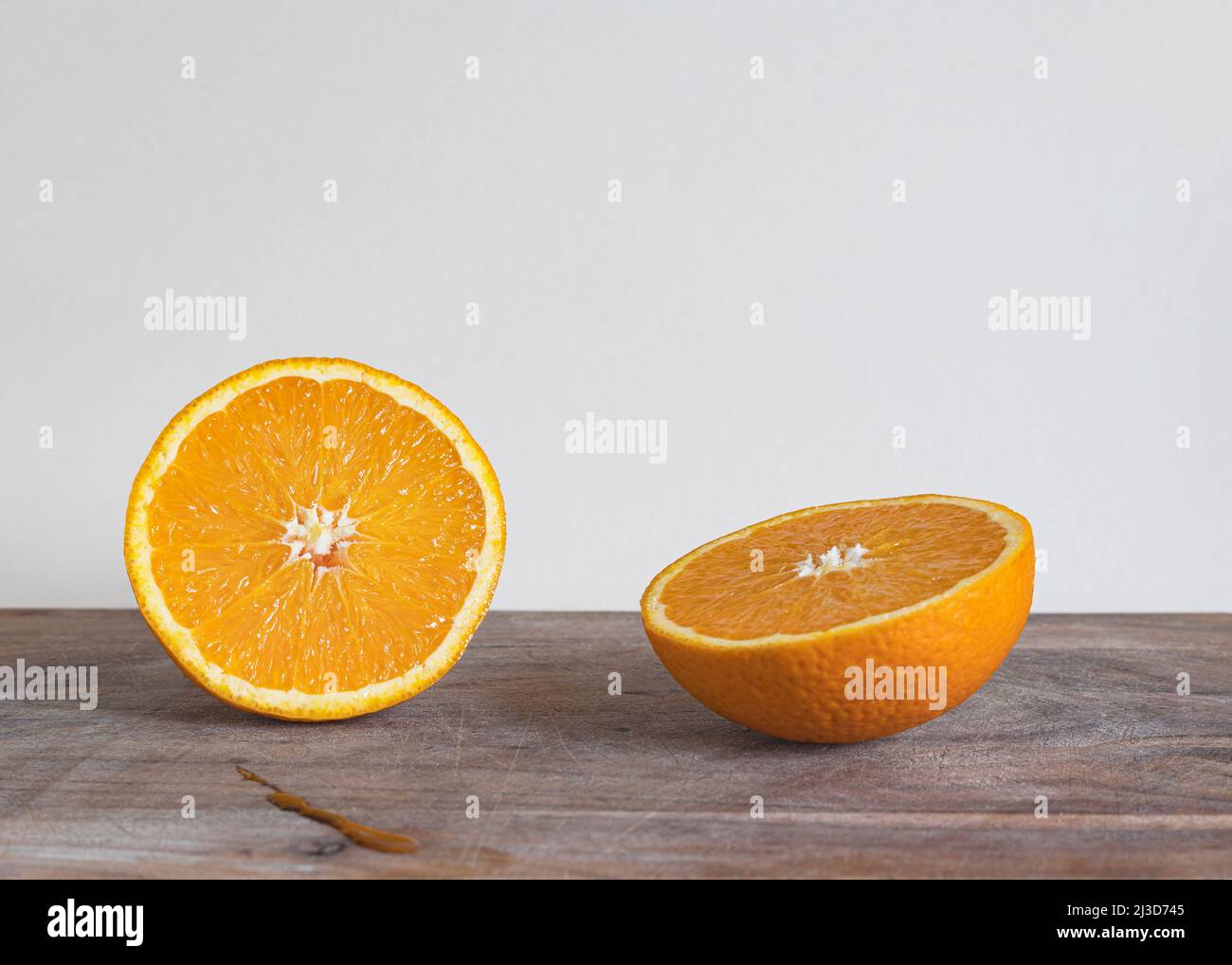 an orange fruit cut in half on a chopping board Stock Photo