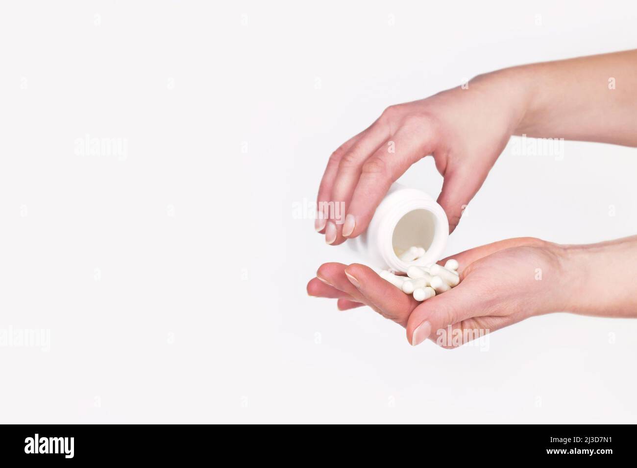 Female hands pouring pills out of white container Stock Photo