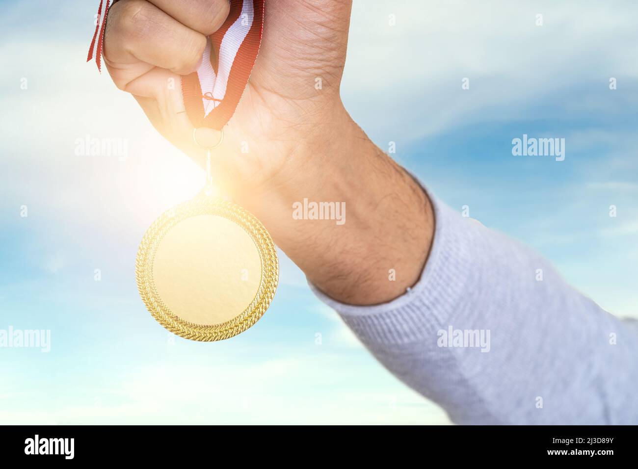Man raising hand and holding gold medal. Concept of ambition perseverance and victory. Stock Photo