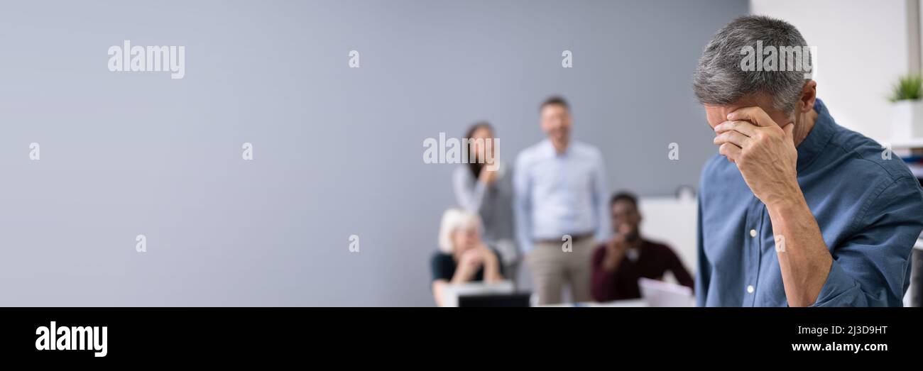 Portrait Of A Sad Businessman With Colleagues Laughing On Her In Background Stock Photo