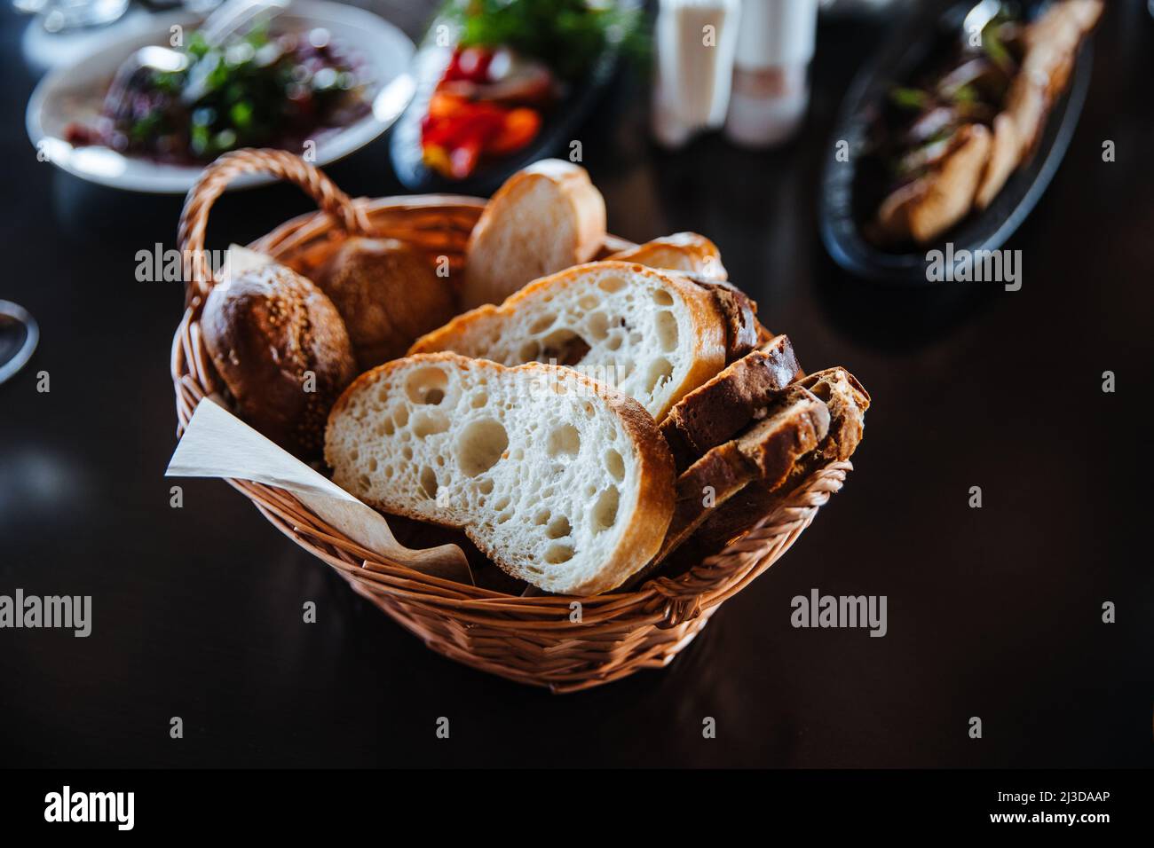 Different types of bread in the basket on the table in the interior of the restaurant. Stock Photo