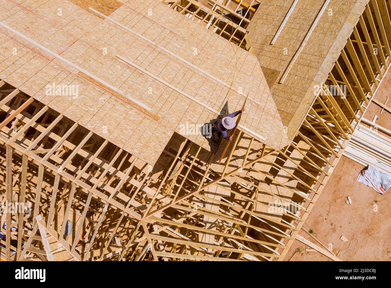 Construction worker putting the plywood with nail gun on a house ...