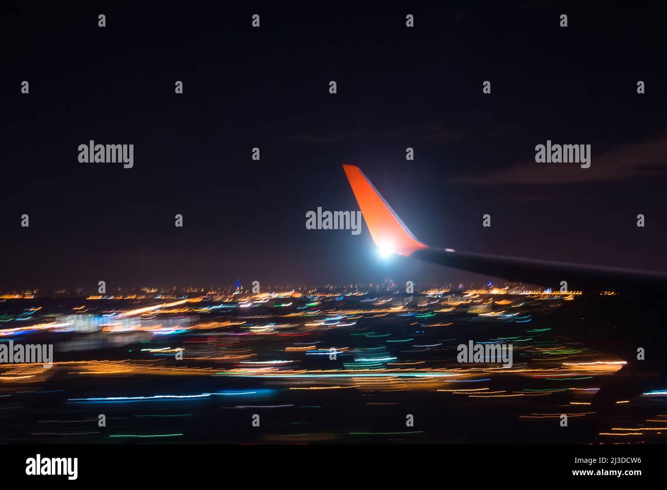 Night landing approach airport over city lights, view of the wing of the aircraft, shooting with a long exposure Stock Photo