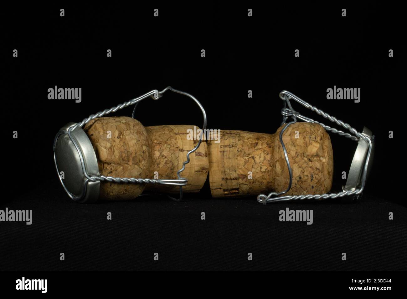 two sparkling wine corks inside wire cages isolated on a black