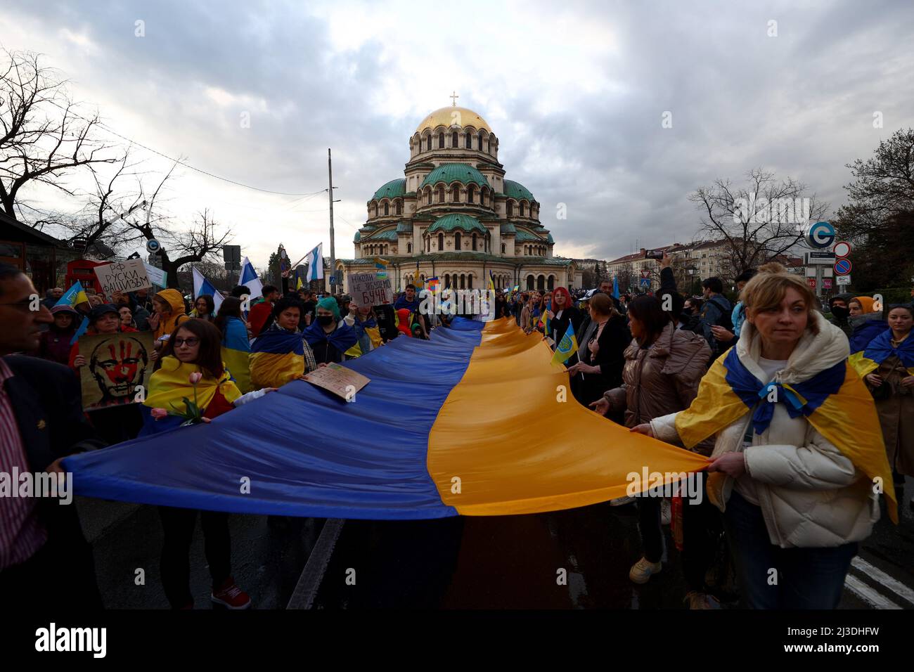 Sofia, Bulgaria - 7 April, 2022: People demonstrate holding Ukraine's national flag during a march in support of Ukraine. On 24th of February Russian army entered Ukrainian territory in what the Russian president Vladimir Putin declared a 'special military operation'. Stock Photo