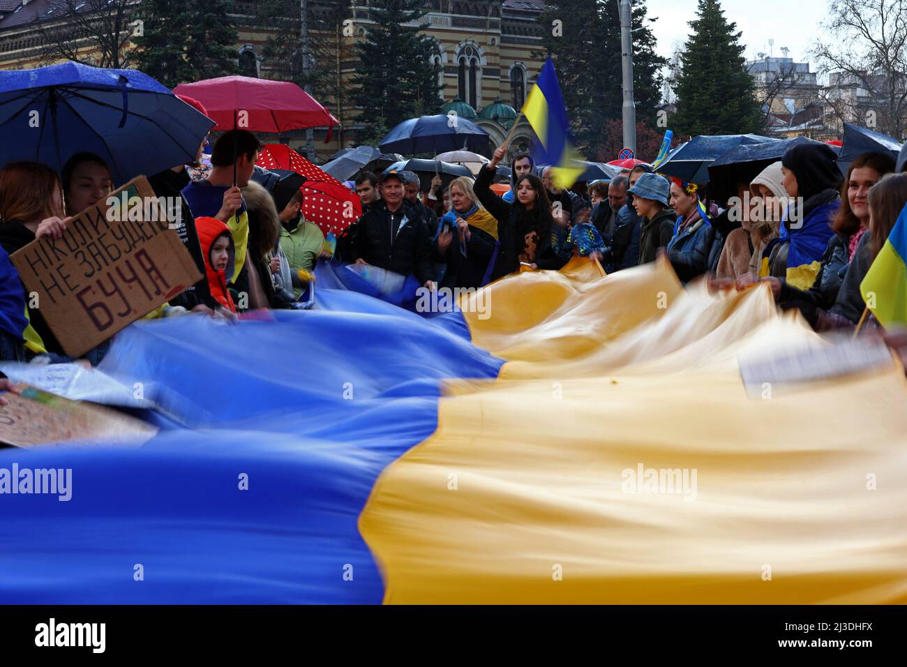 Sofia, Bulgaria - 7 April, 2022: People demonstrate holding Ukraine's national flag during a march in support of Ukraine. On 24th of February Russian army entered Ukrainian territory in what the Russian president Vladimir Putin declared a 'special military operation'. Stock Photo