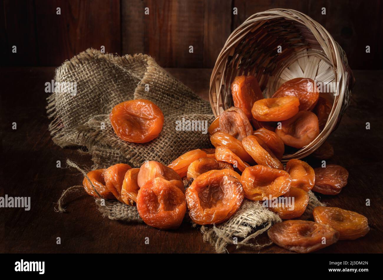 dried apricots in a basket on a dark wooden background Stock Photo