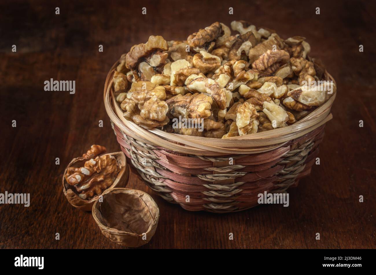 walnuts and kernels in a basket on a dark wooden background Stock Photo