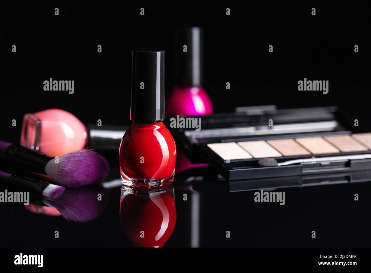 Set of cosmetic makeup products. Eyeshadow, nail polish and makeup brushes on a black table. Stock Photo