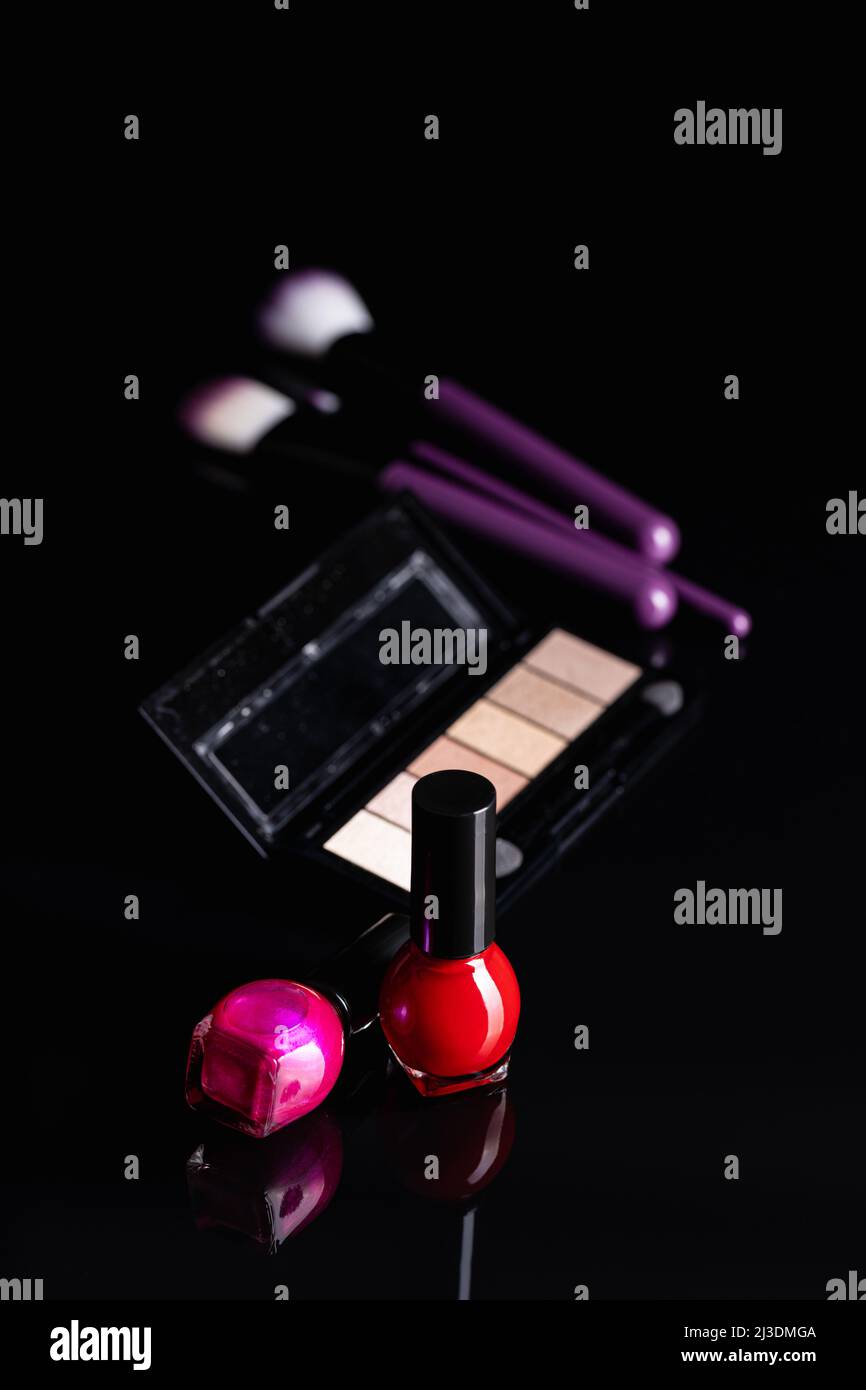Set of cosmetic makeup products. Eyeshadow, nail polish and makeup brushes on a black table. Stock Photo