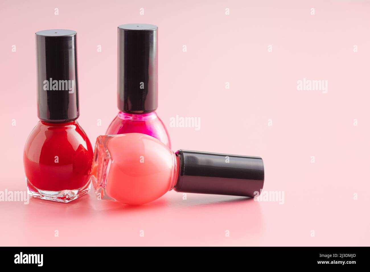 Colorful nail polish bottles on a pink background. Stock Photo