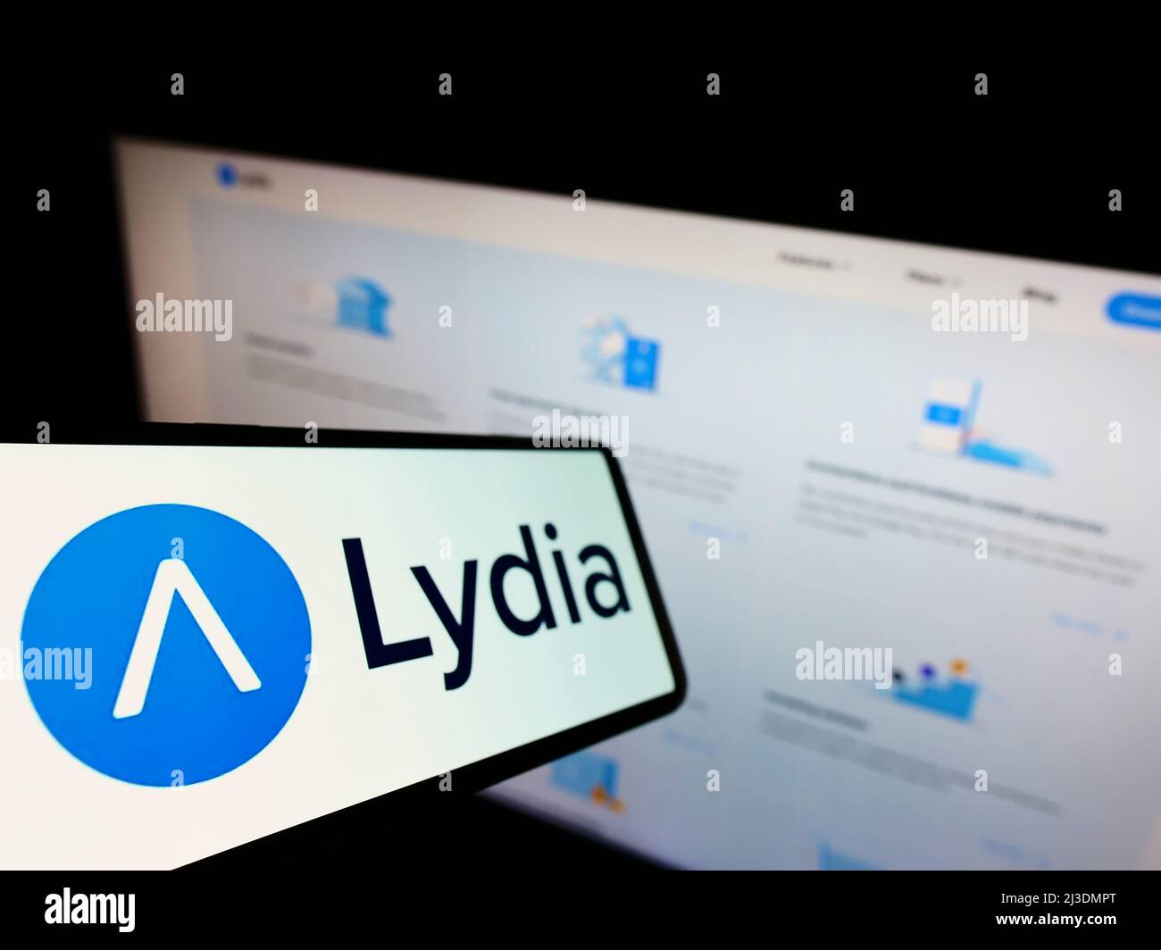 Mobile phone with logo of French company Lydia Solutions SAS on screen in front of business