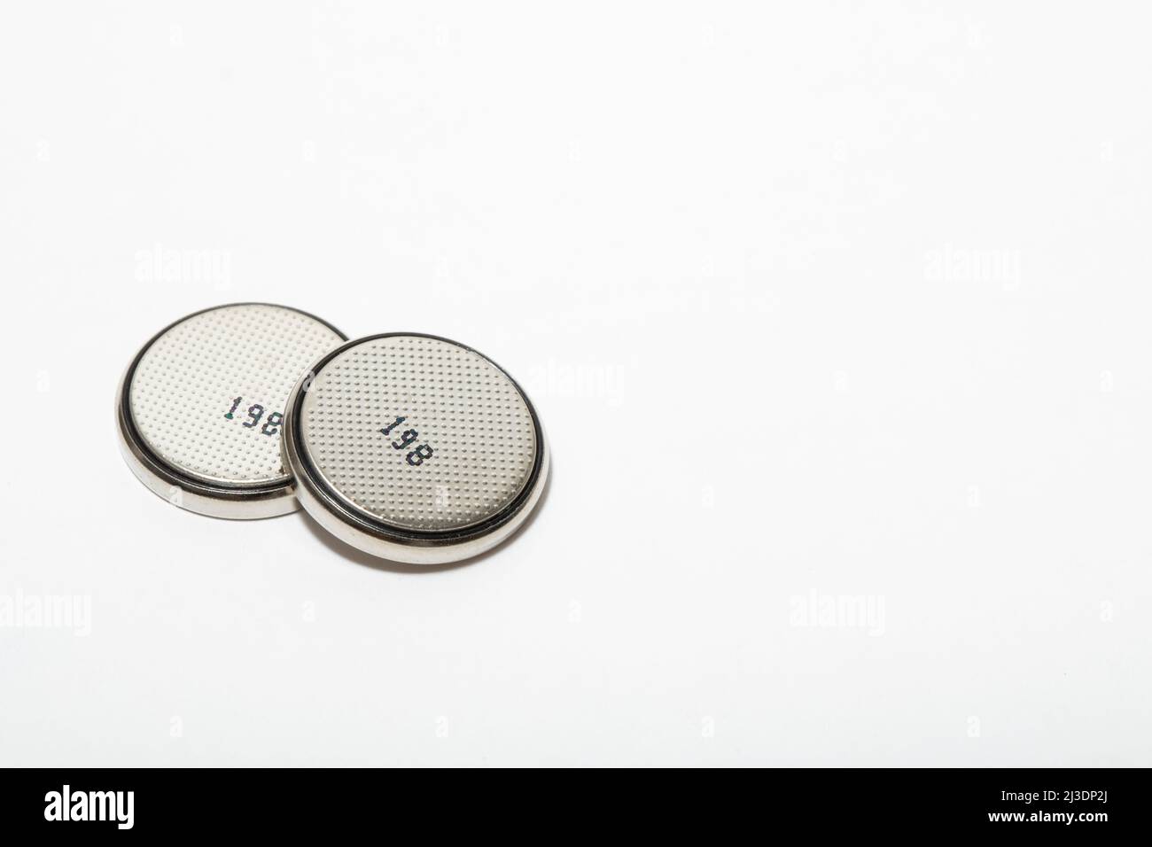 close up macro of two button cell batteries next to each other on a white background Stock Photo