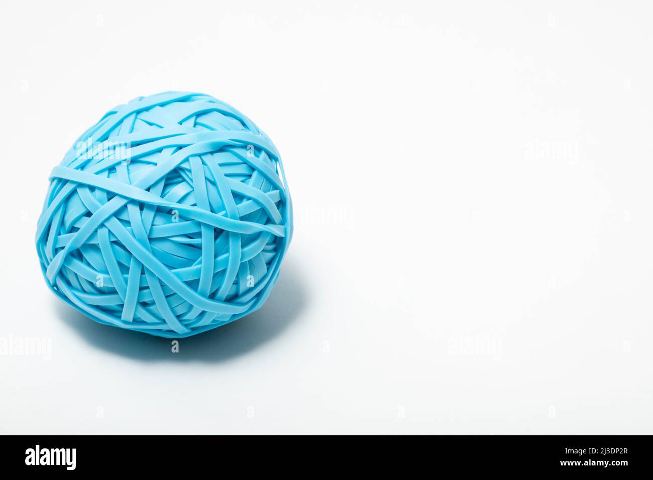 close up macro of a single blue ball of many rubber bands on a white background Stock Photo