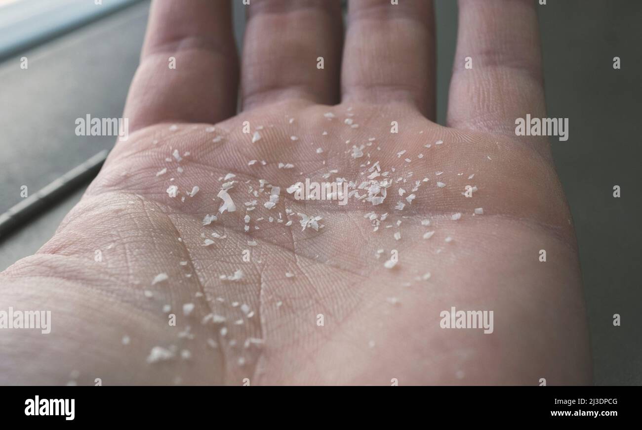 Close-up side shot of microplastics on human fingers. Concept for water pollution and global warming. Climate change idea. Stock Photo