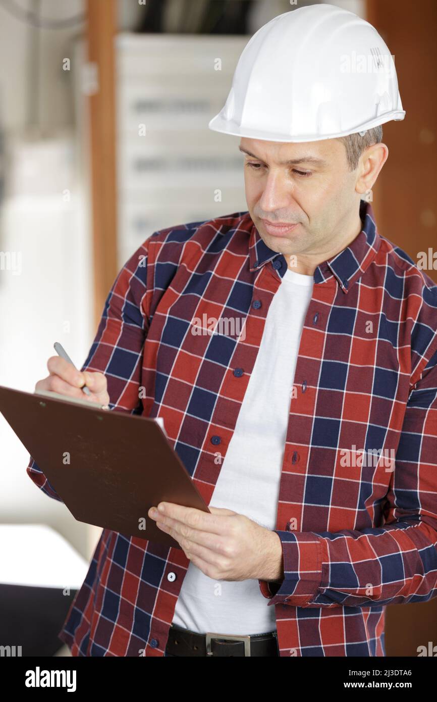 mature tradesman writing on clipboard Stock Photo