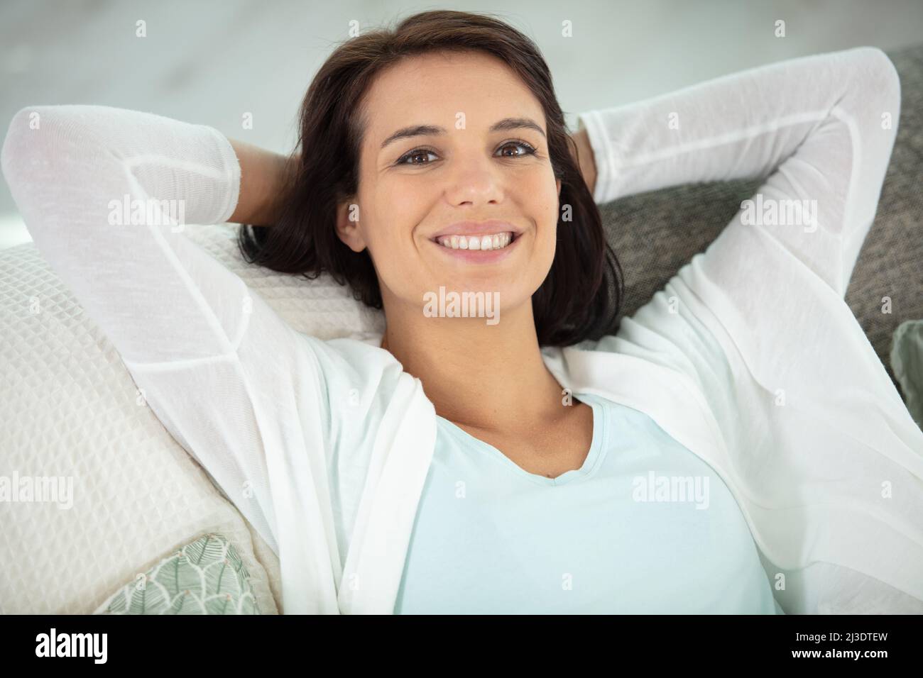 young smiling woman sitting on sofa Stock Photo - Alamy