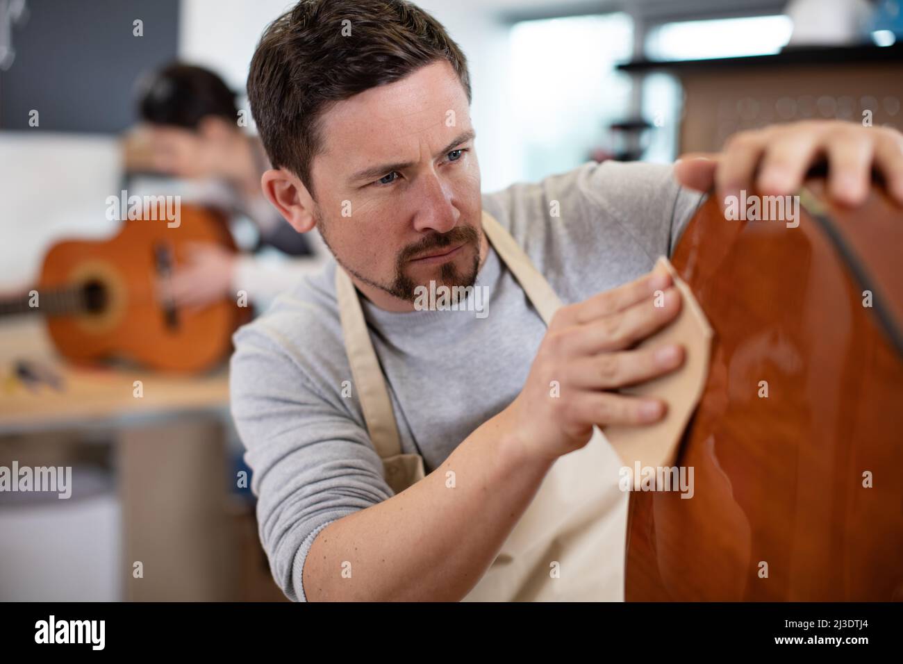 a craftsman sanding a guitar Stock Photo Alamy