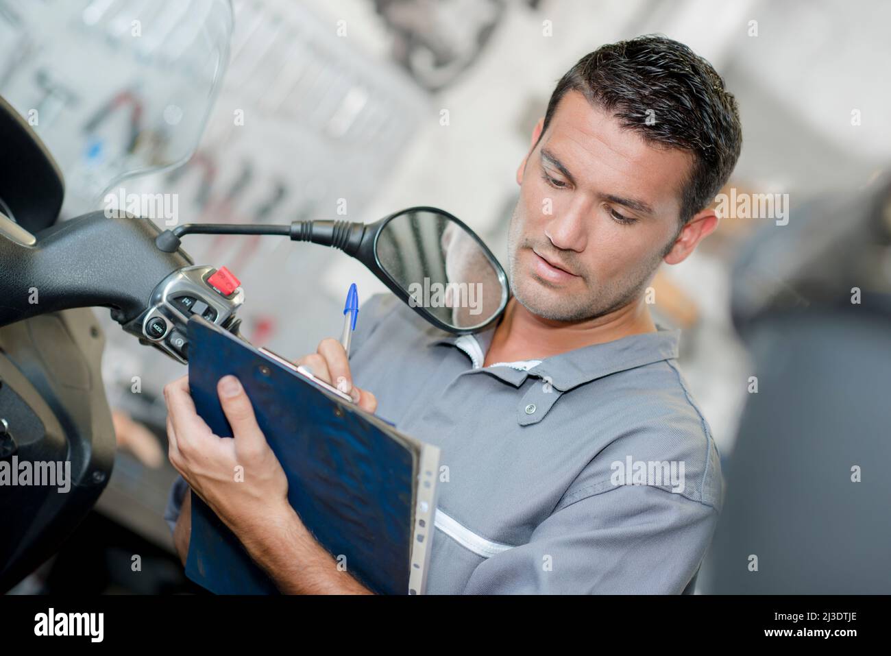 Mechanic making notes on clipboard Stock Photo