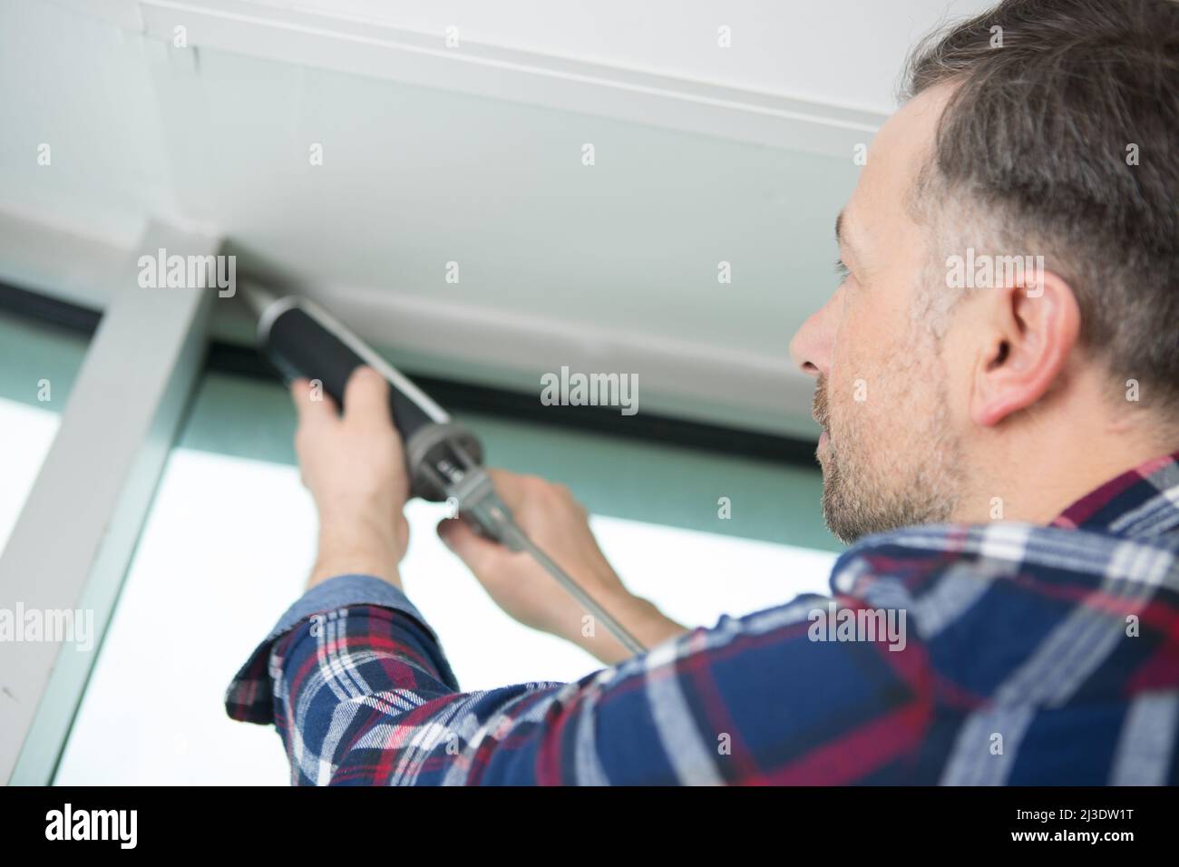man with silicone sealant fixing a window Stock Photo - Alamy